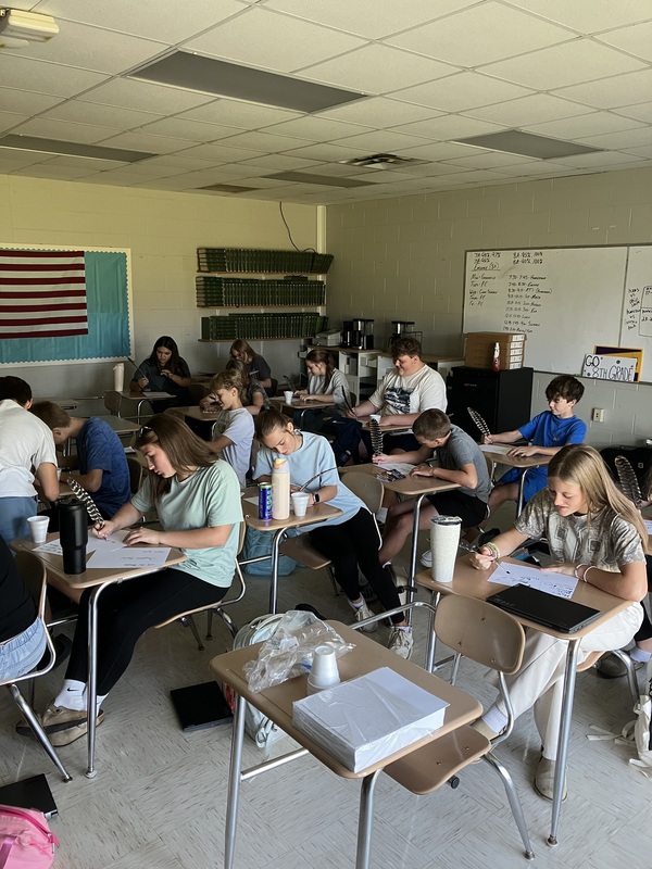 8th grade students practice writing name with feather pens