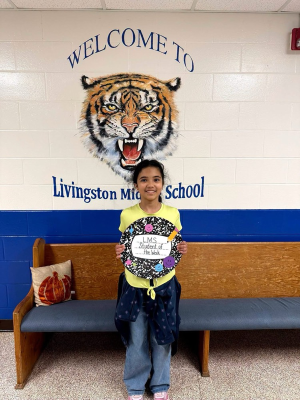 girl holding student of the week sign