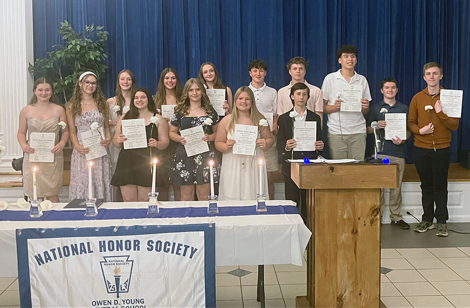 Students stand on the stage holding National Honor Society certificates