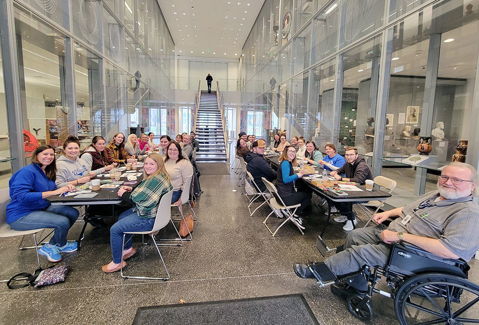 groups of teachers seated at tables in museum creating artwork