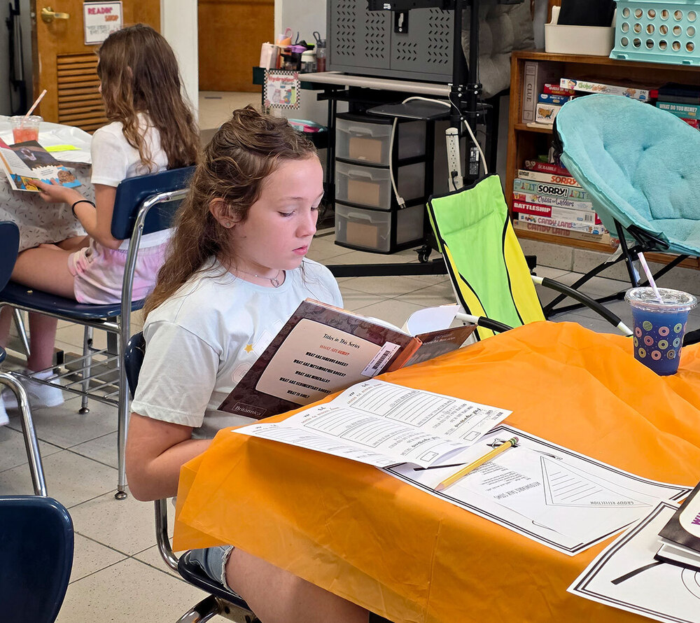 A student reads a book while seated at a desk