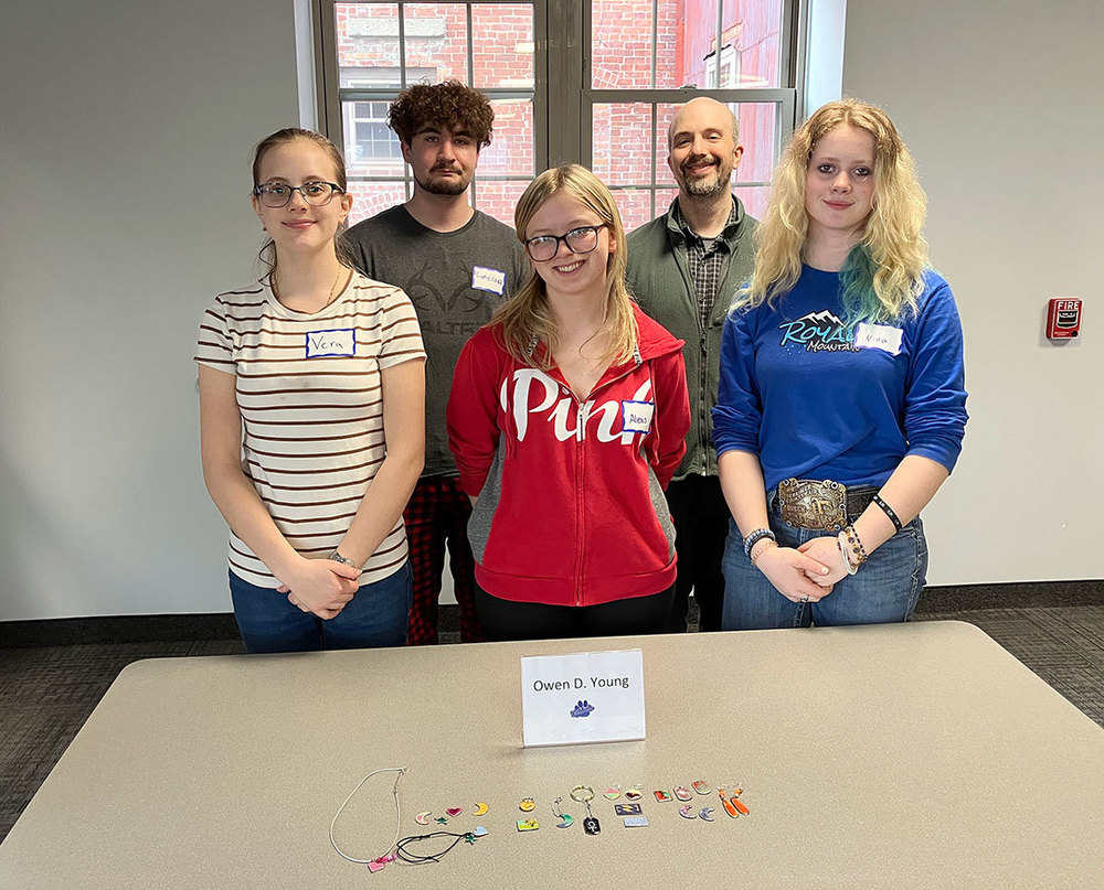 four students and teacher stand behind table with jewelry on display