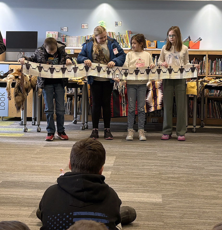 Four students help display an artifact from the Oneida Indian Nation