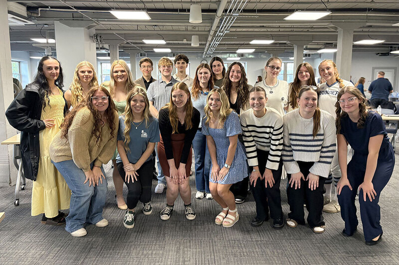 A group of approximately 20 students huddle together for a picture at the ACIE completion ceremony