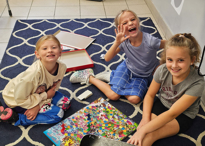 three students play a board game