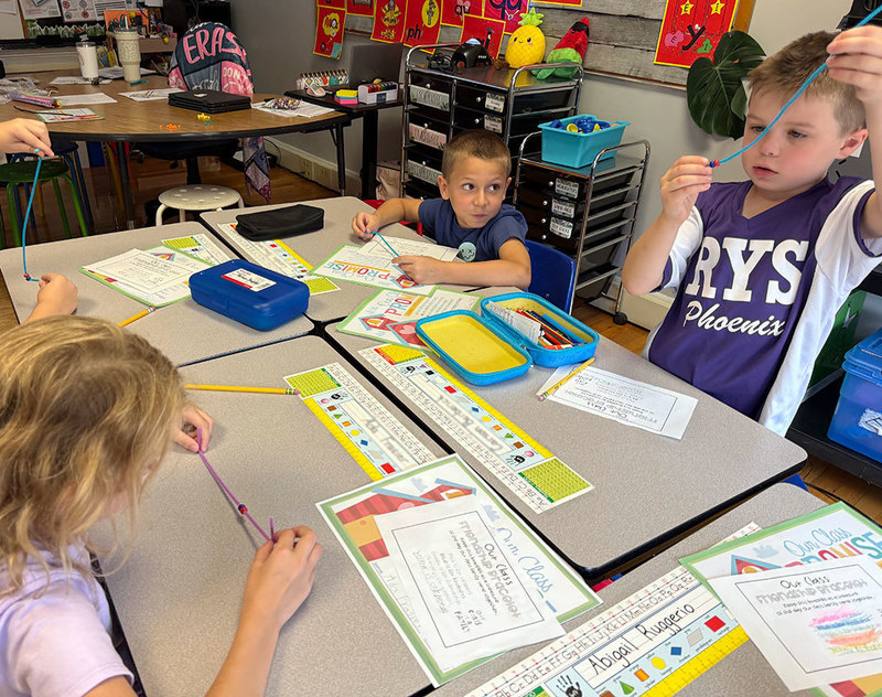 Students sit at desks building bracelets