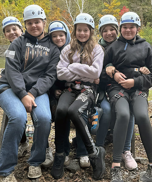 a group of students wearing helmuts sit close together and smile