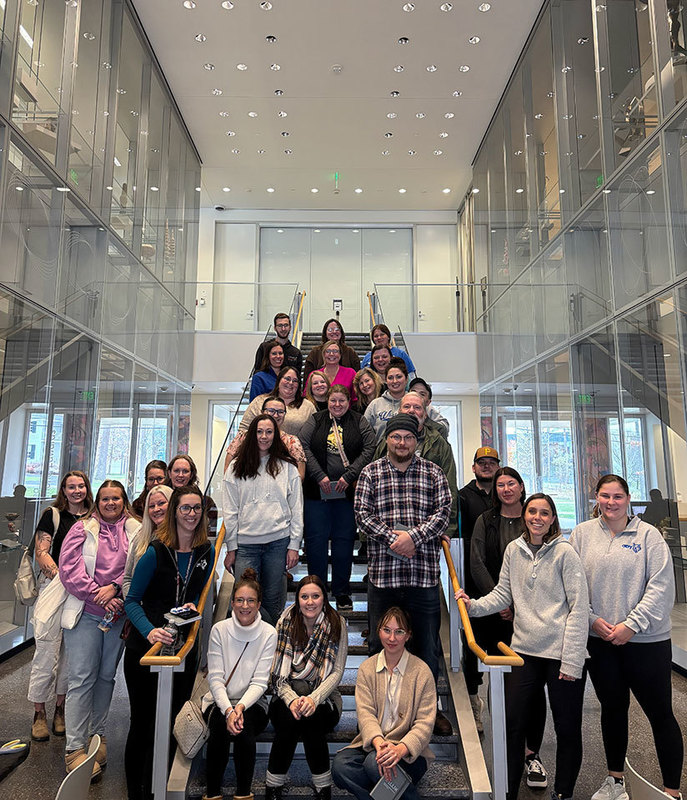 large group of educators stand together on a staircase in museum