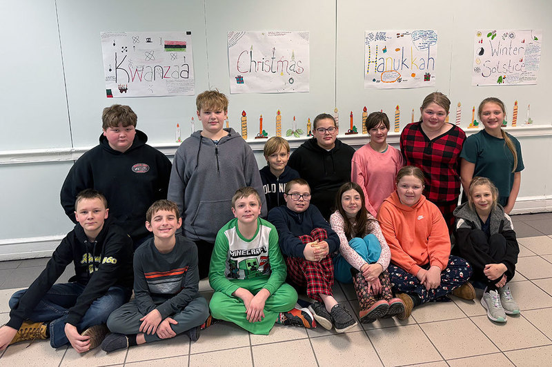 grade 6 students sit in the hallway in front of holiday display