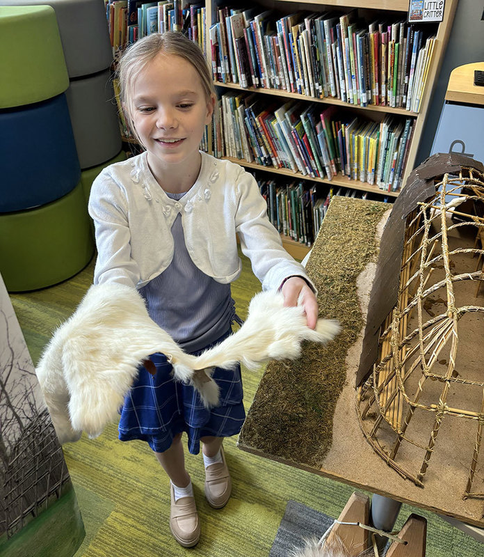 A student holds an animal pelt during the Oneida Indian Nation presentation