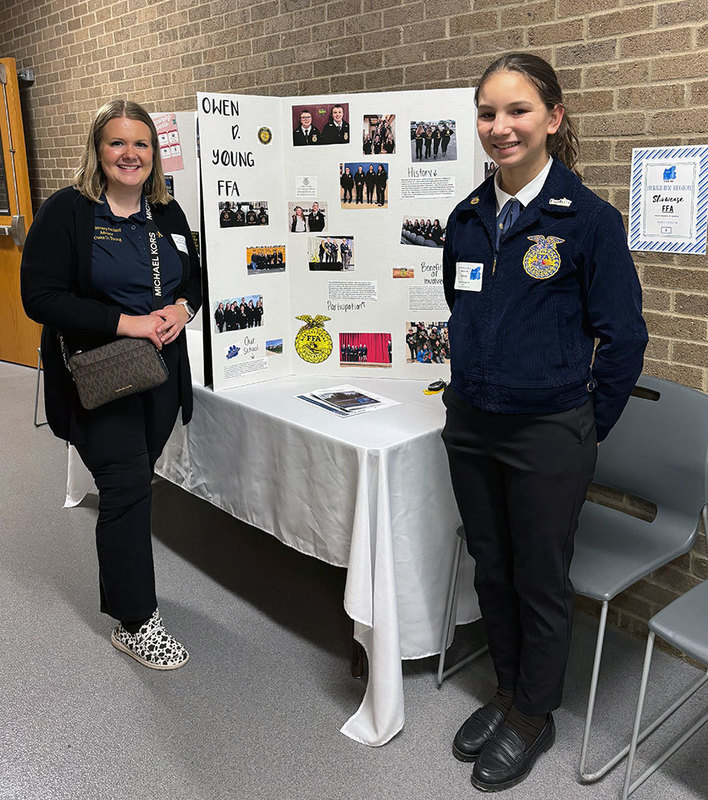 FFA advisor and student stand in front of display 
