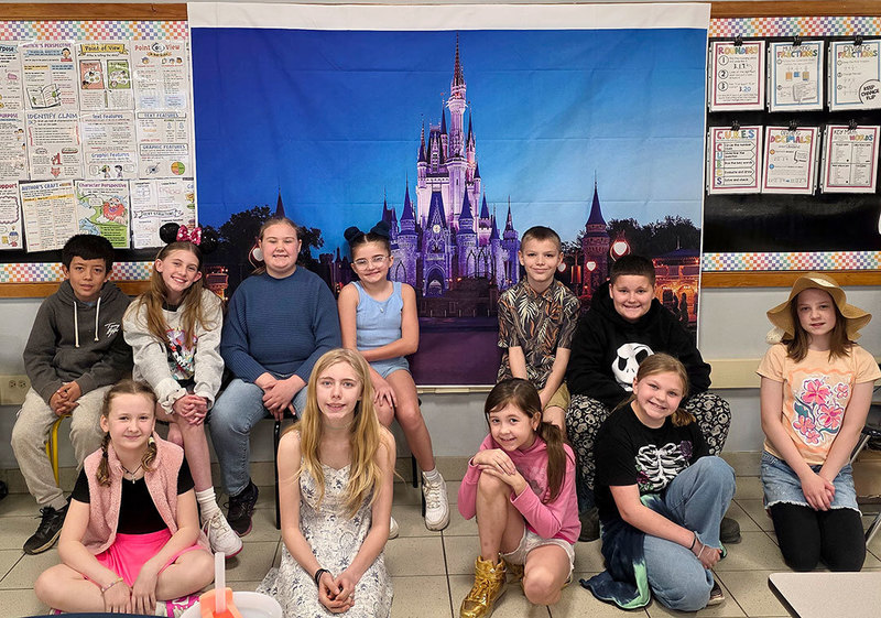 A group of students sits in front of an image of the famous Disney Castle that is projected on a screen  behind
