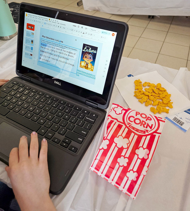A reading activity appears on a laptop screen that is open on a desk