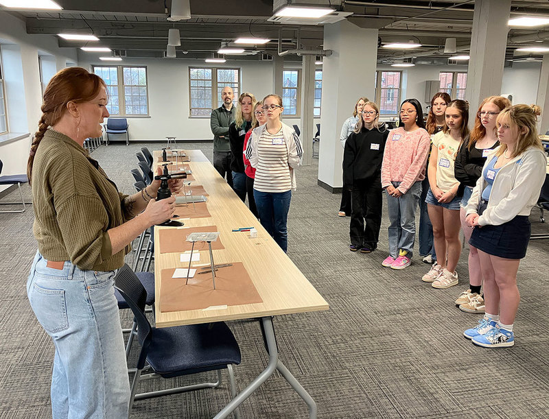 artists stands in front of students to demonstrate  a torch