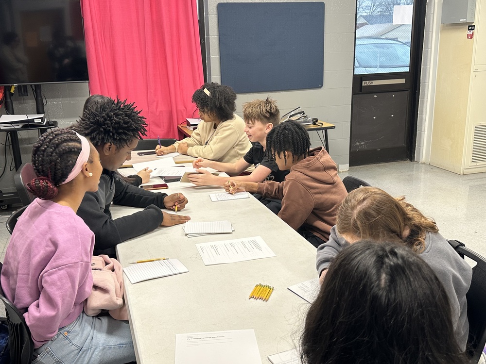 Students sitting around table working on worksheets