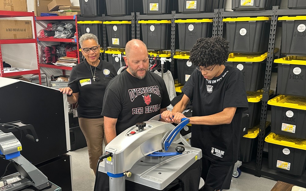 Three people working tshirt press