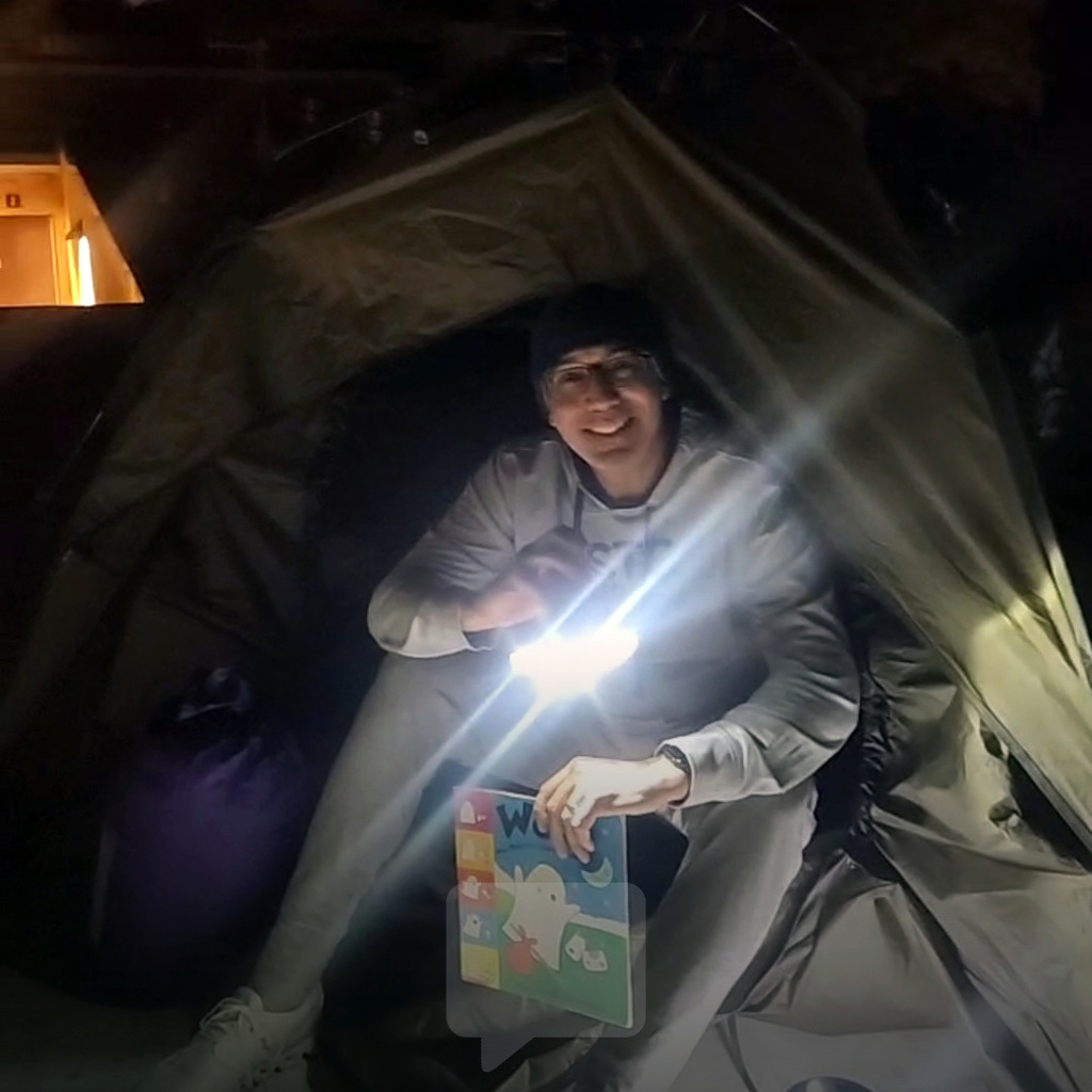 Mr. Kaye Smiling in a Tent with a Book