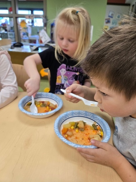 Two preschoolers eating soup