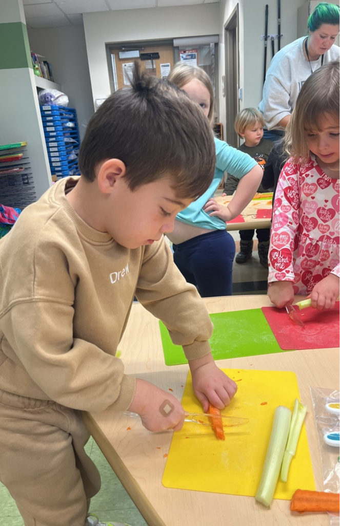 Boy cutting carrot with plastic knife