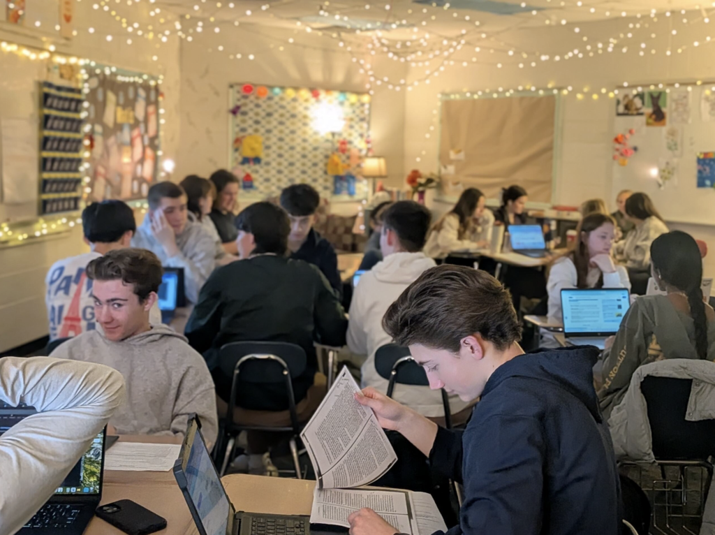 students working together on laptops and reading a paper