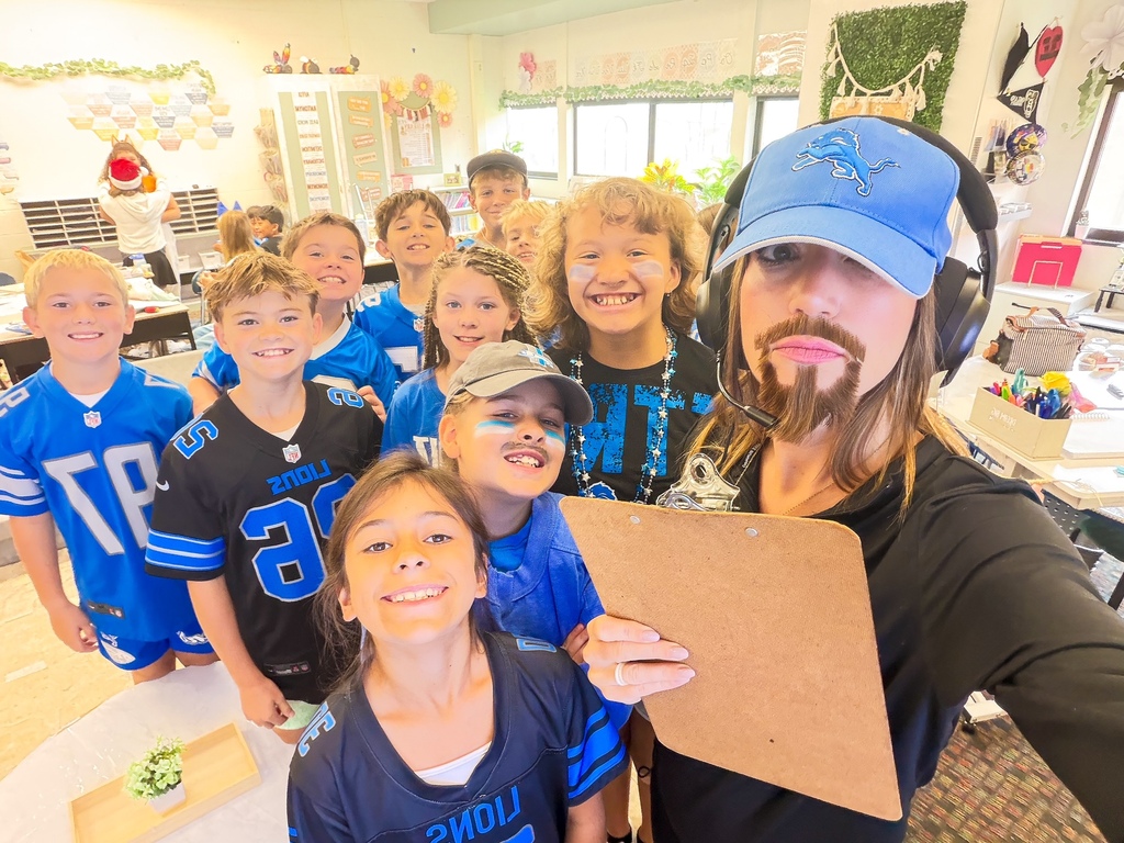 elementary students smiling for a photo wearing lion's football gear
