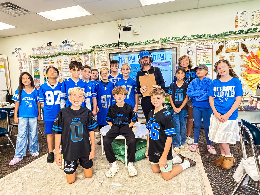 elementary students smiling for a photo wearing lion's football gear