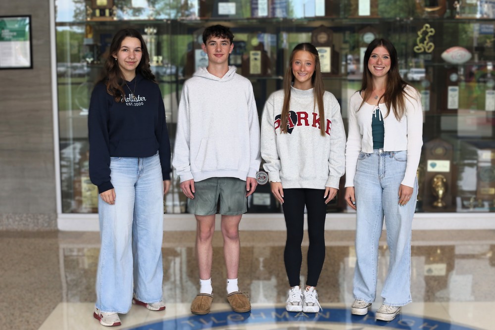 Students stand in a lobby in front of a trophy case