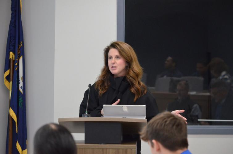 A woman stands speaking at a lectern