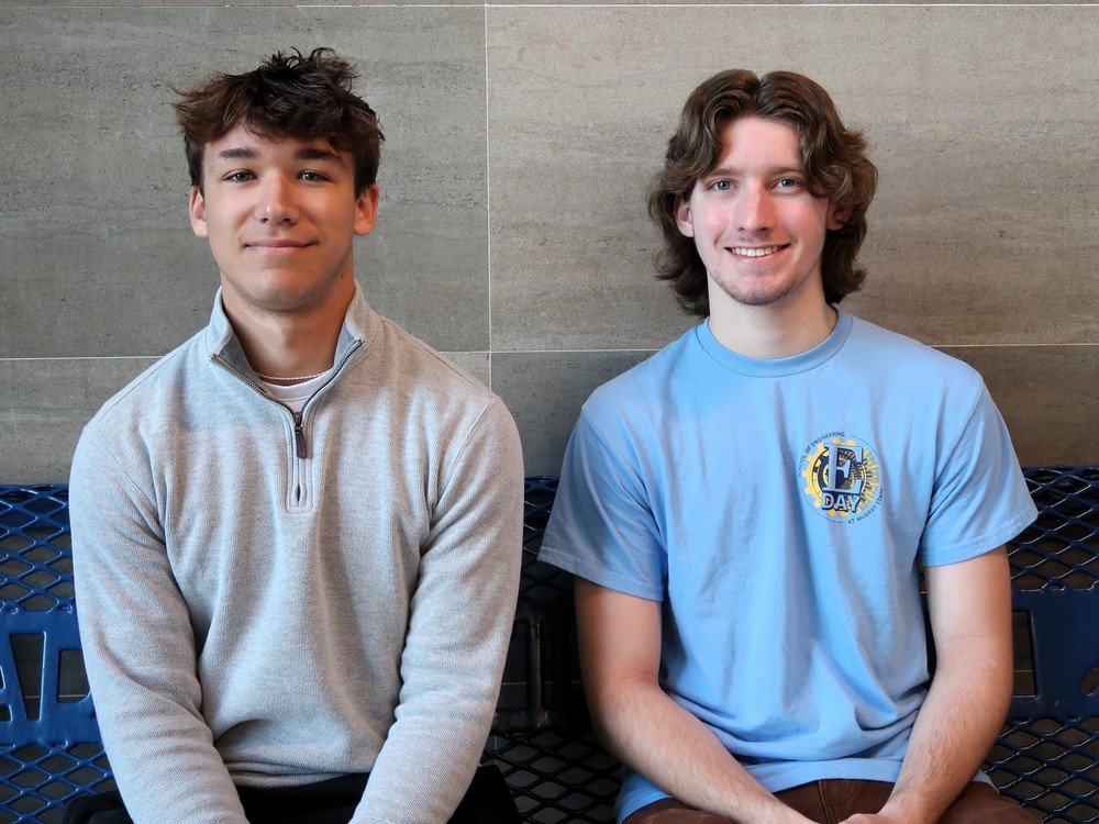Two students sit on a bench 