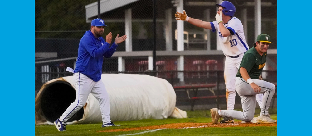 A baseball coach claps as a player makes it to base