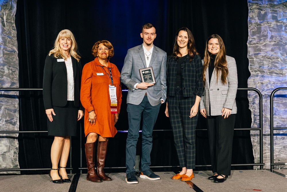 as student with a plaque stands with a group of adults