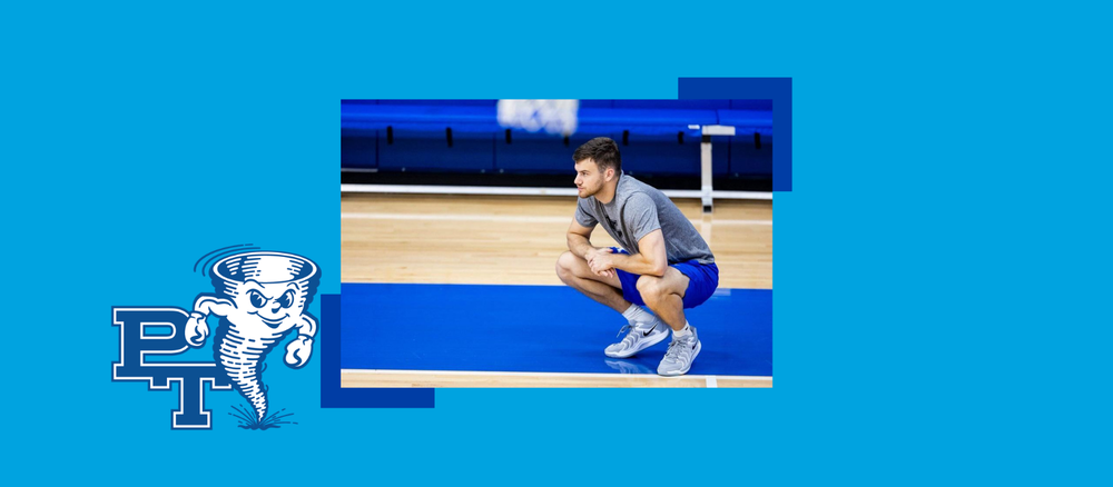 A basketball player squats on the gym floor