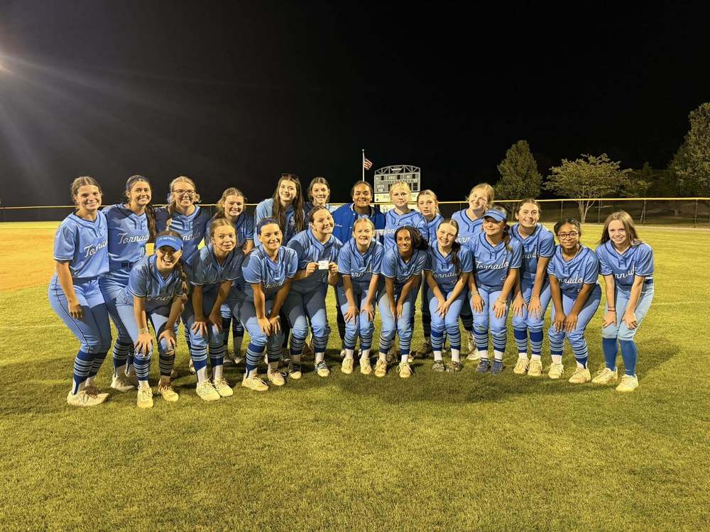 A softball team looks at the camera from the outfield