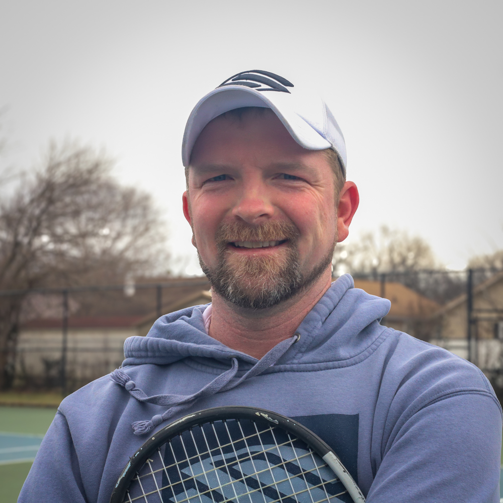 a man stands on a tennis court holding a tennis racket