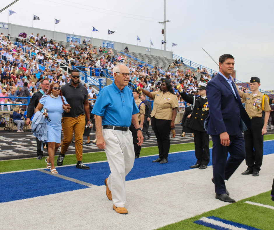 Honorees walking on a football field.
