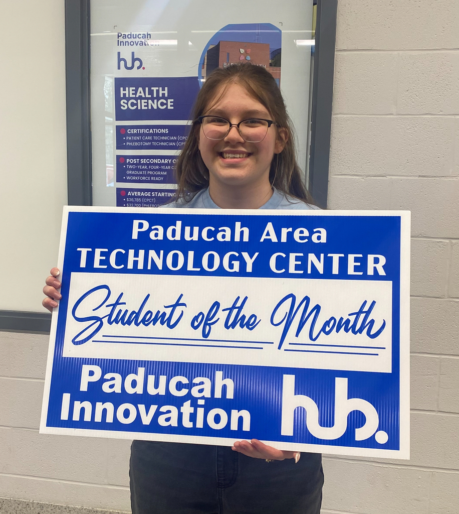 Person holding a sign with "Student of the Month" in blue and white letters. Sign reads "Paducah Area Technology Center" and "Paducah Innovation Hub".
