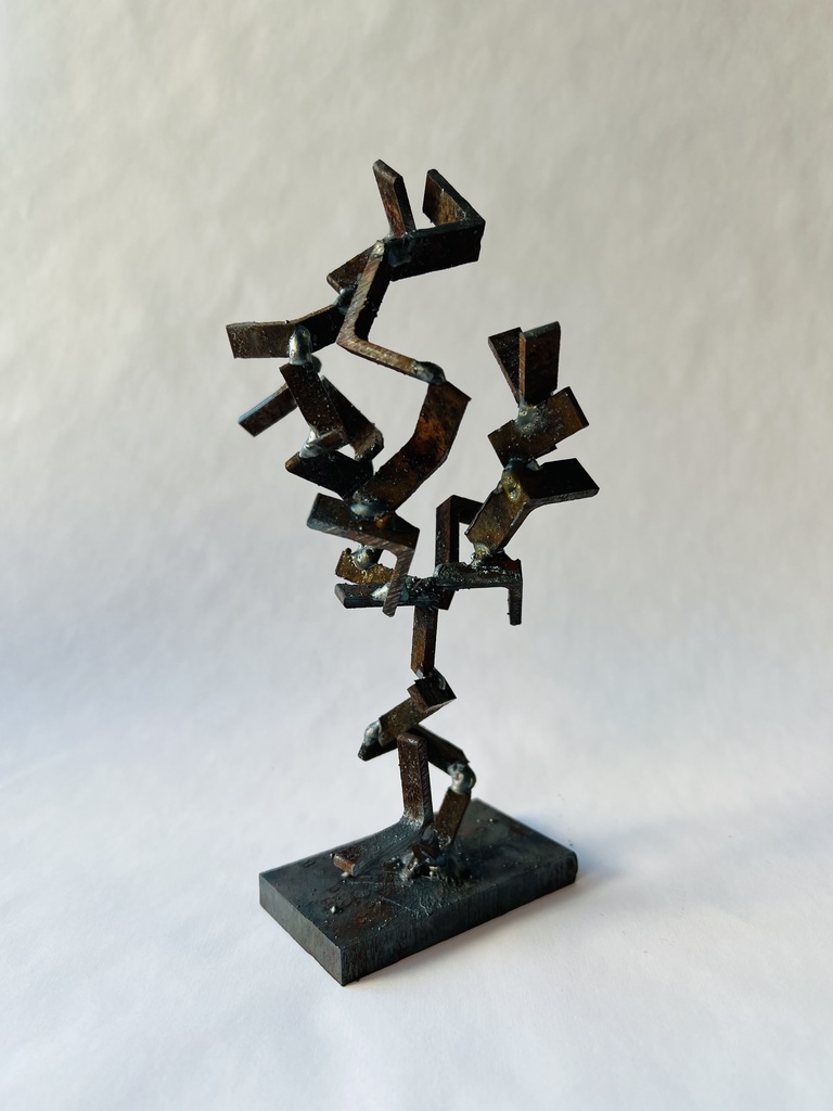 A metal sculpture with abstract shapes on a white background. The sculpture is dark and has various angles.