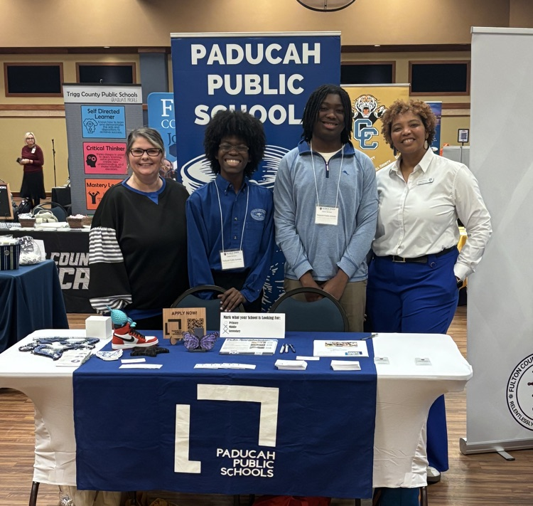 People standing behind a display table.