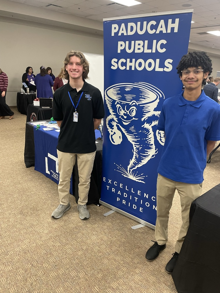 Two teenagers standing by a banner.