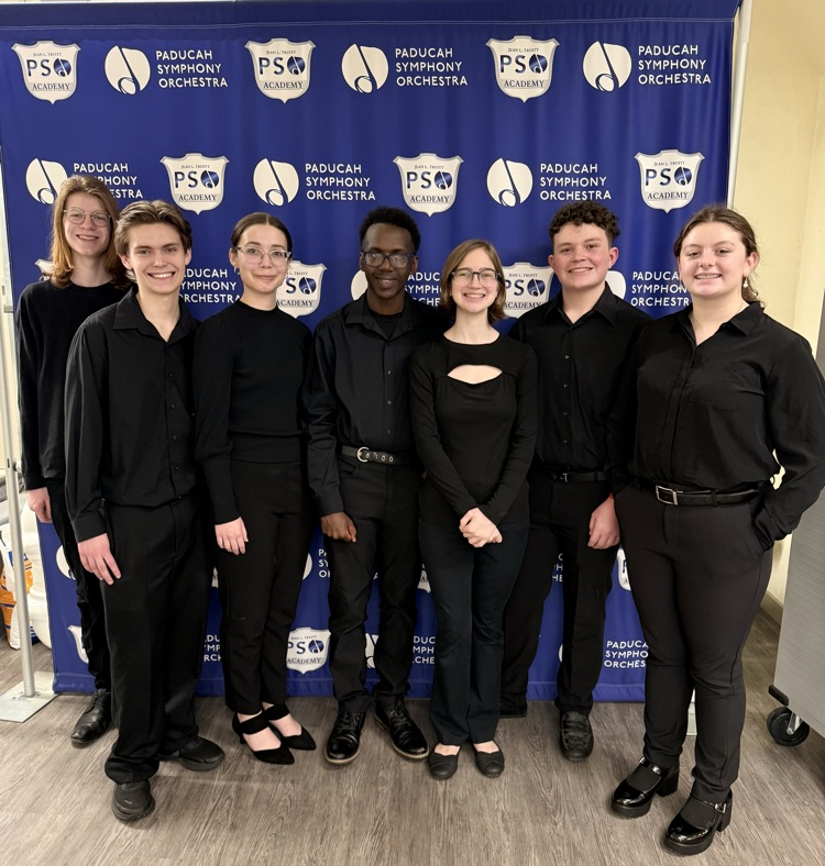 Group of young musicians in front of a blue backdrop.