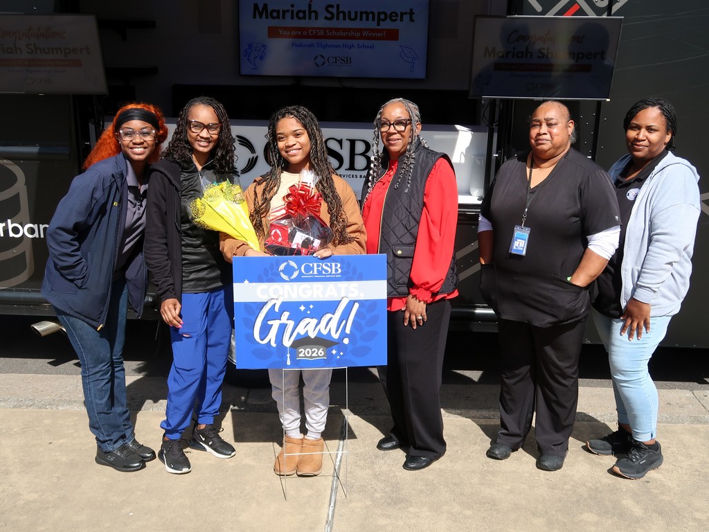 Six women stand in front of a building, with one holding a blue sign that says "Grad! 2019".