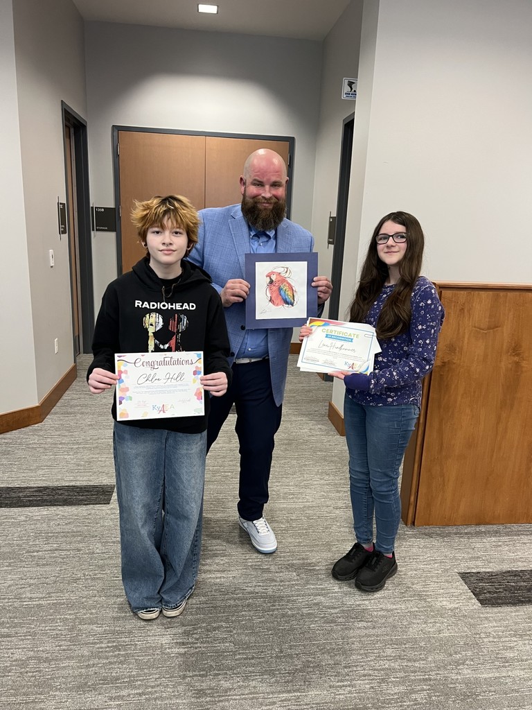 Three people in a corridor: a man with a beard and a blue suit, a boy in a black hoodie, and a girl in a blue long-sleeve shirt.