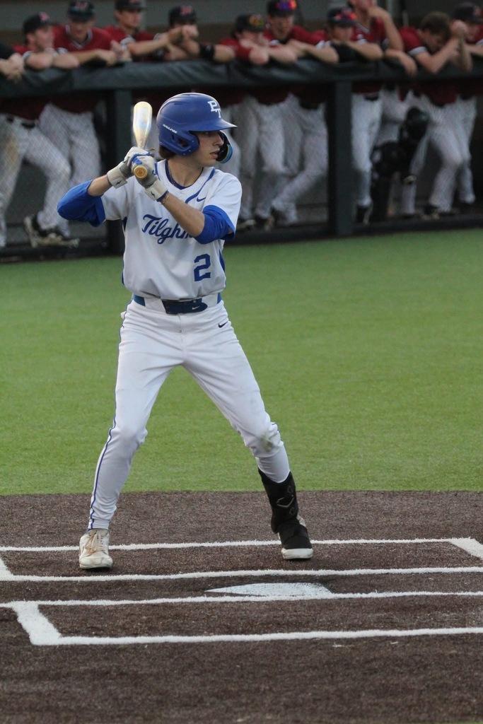 Player in blue helmet and white uniform with number 2 stands in batter's box, holding baseball bat.