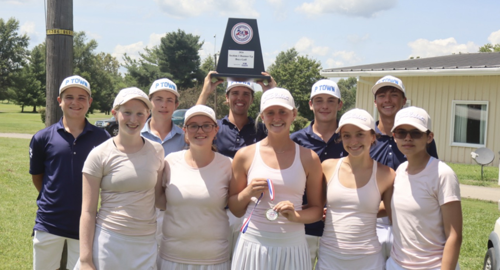 A group of people in matching white tops and hats pose with a trophy in a grassy area.