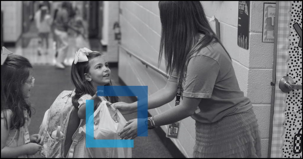 A black and white photo of a woman adjusting a young girl's hair in a hallway.