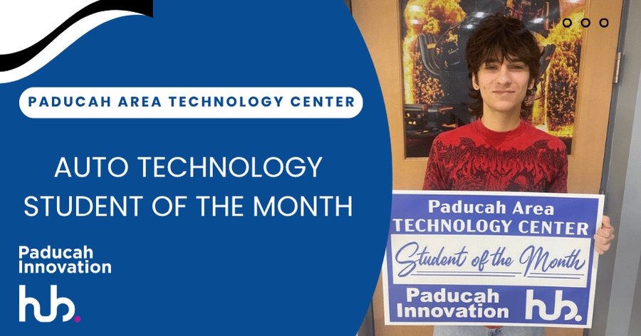 A student holds a sign saying Paducah Area Technology Center Student of the Month in front of a red-orange background.