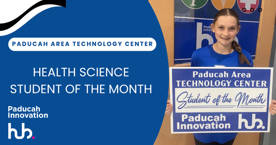 A student stands in front of a blue sign, holding a certificate that reads "Student of the Month".