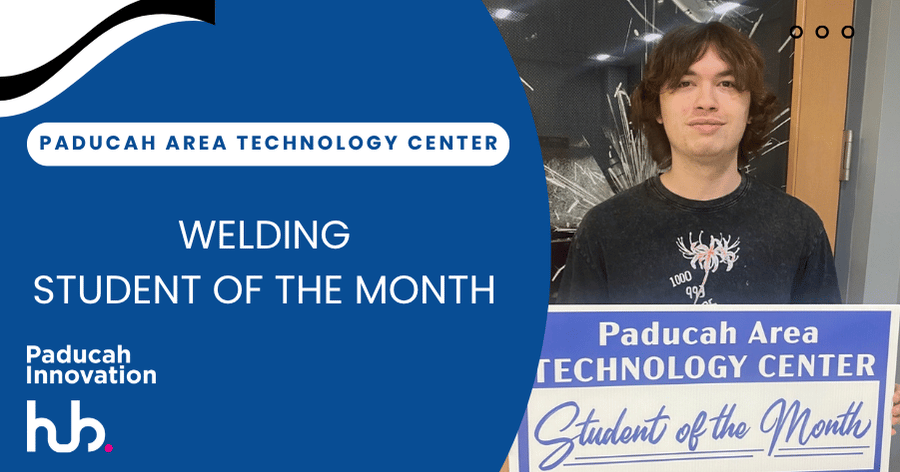 Person with dark hair stands next to blue sign reading Welding Student of the Month. Person holds sign with blue background and white text.