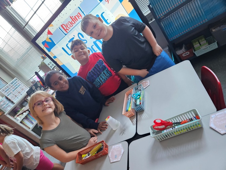     Four third graders smile beside their table after successfully saving Fred.