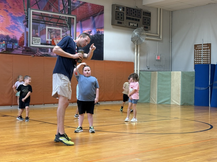 PE teacher gives group of first graders directions for the activity they will be doing.